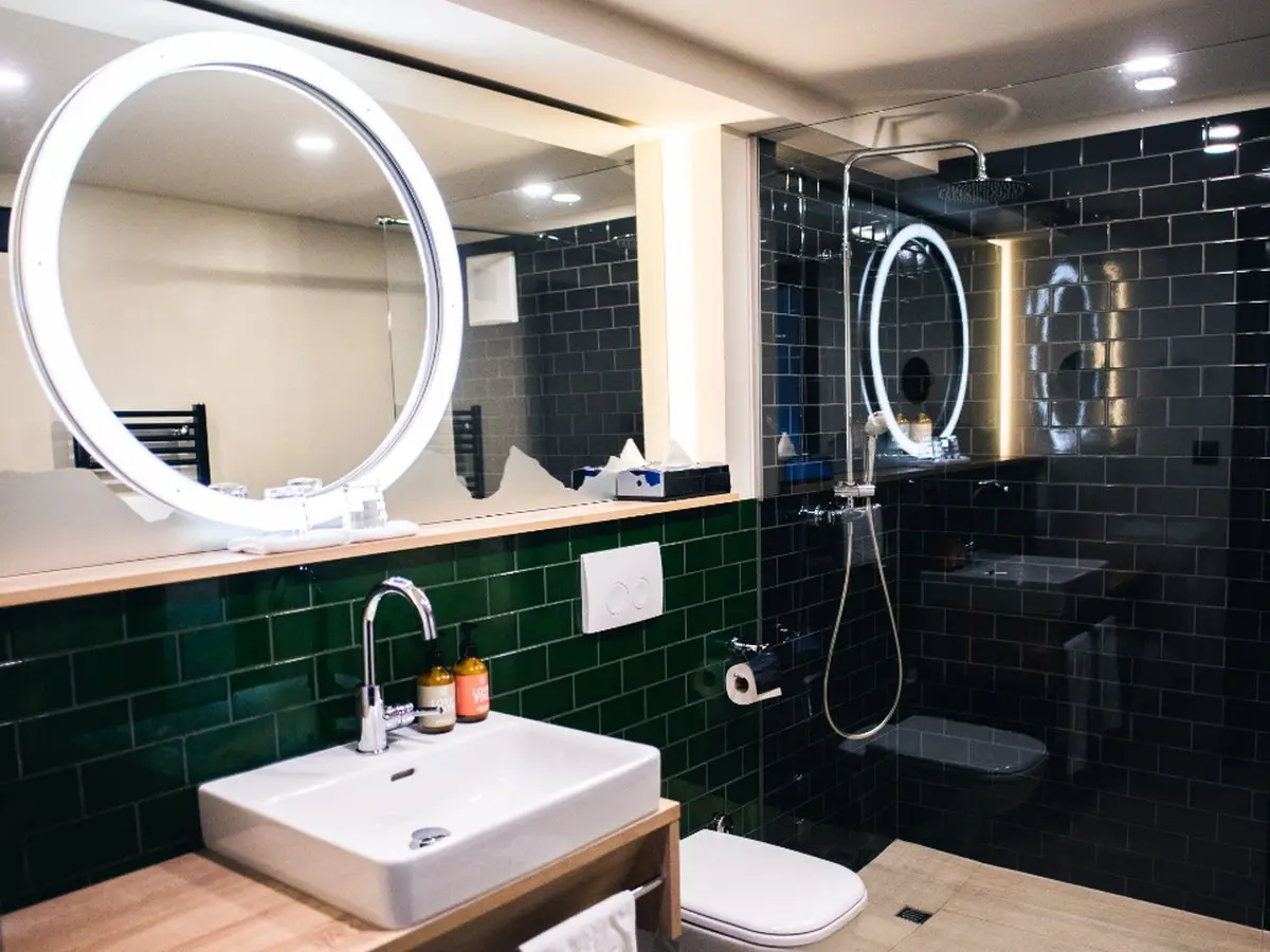 A finished bathroom with green subway tile, a floating vanity and a walk-in shower
