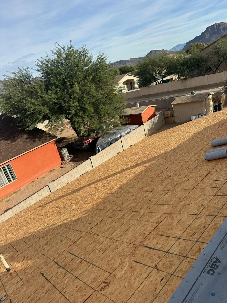 Roof torn off down to new decking, underlayment rolls staged on top