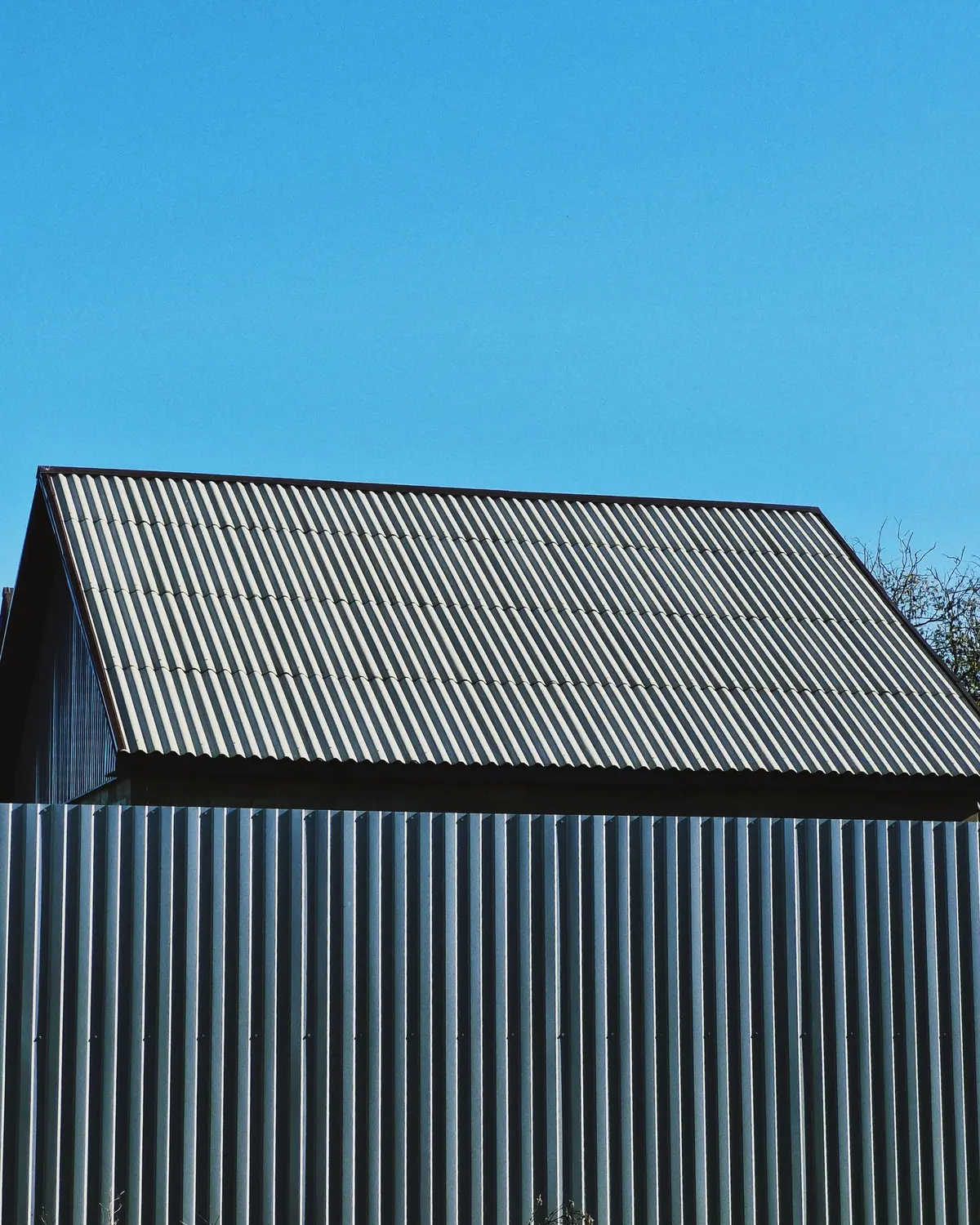 A corrugated metal roof and wall against a clear blue sky